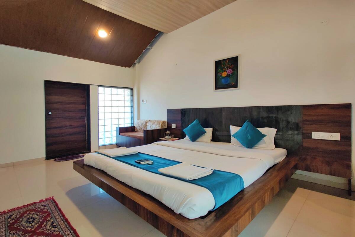 A spacious bedroom with a large bed, a wooden headboard, and a window with a view.