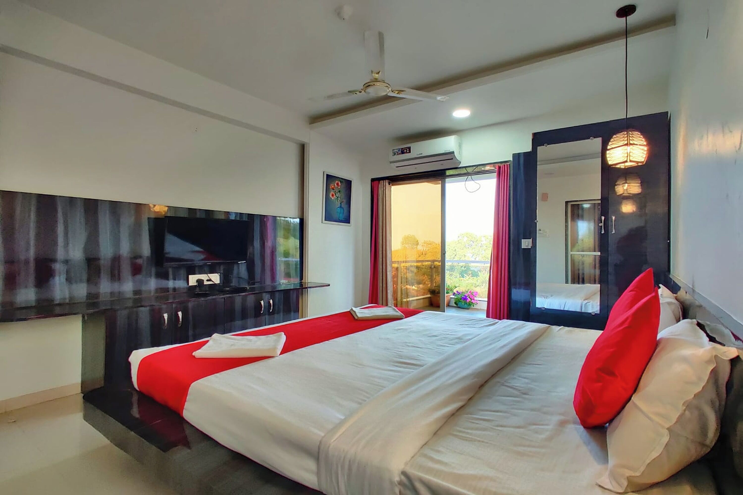 Een hotelkamer met een bed, een televisie, een plafondventilator en een airconditioner.