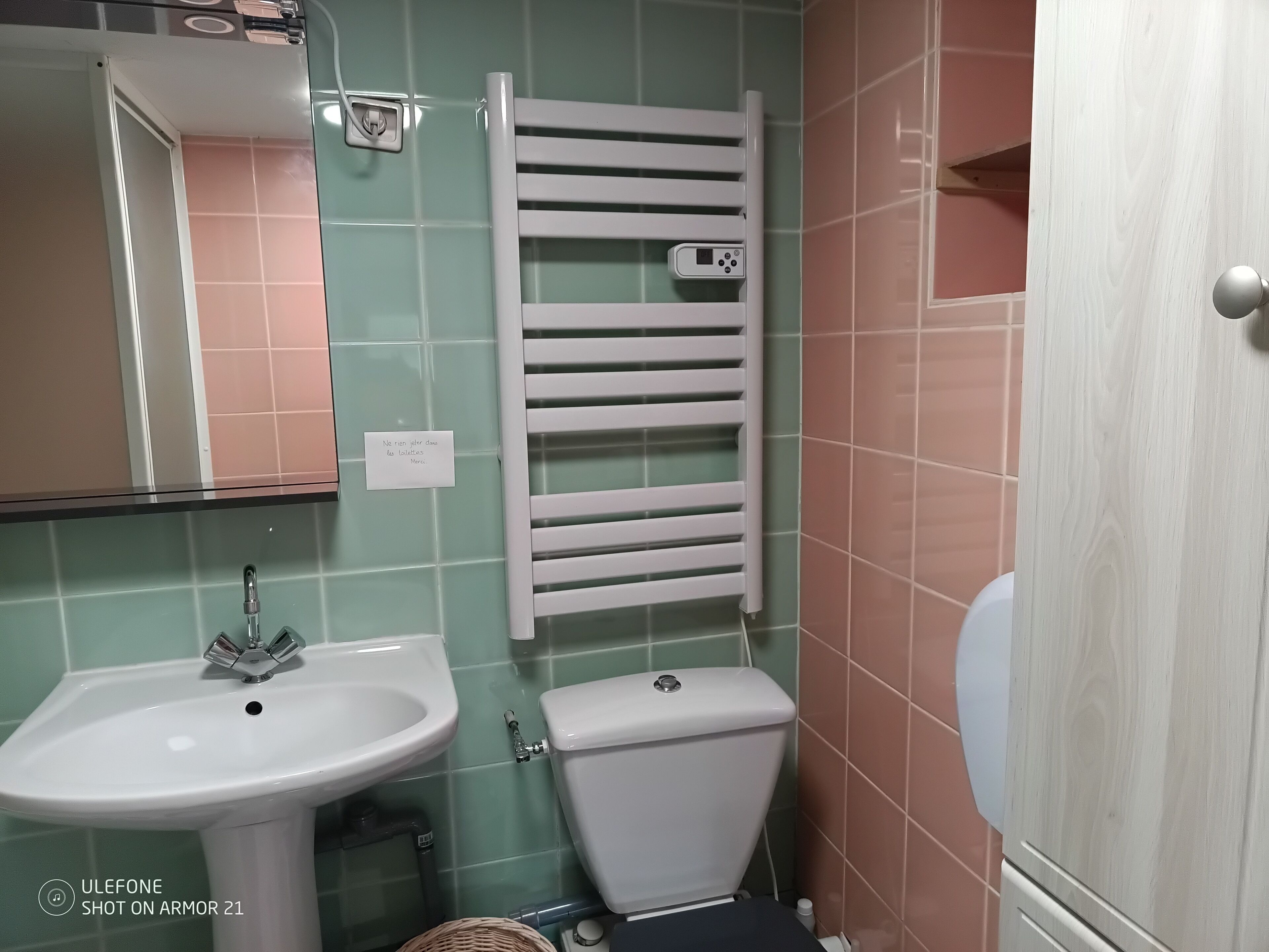 Et badeværelse med et hvidt håndvask, toilet og et håndklædestativ.