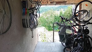 Un espace abrité pour entreposer les vélos, où se trouvent plusieurs vélos, et d’où l’on peut admirer un paysage verdoyant.