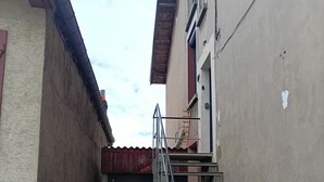 Une ruelle étroite avec un escalier métallique menant à l’entrée d’un immeuble.