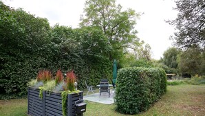 Um espaço de jardim com um banco de madeira, mesa e cadeiras.