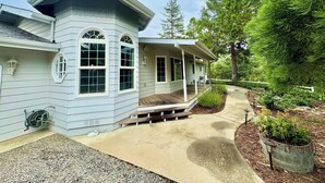 A light blue house with a porch, large windows, and a bird sculpture on the roof. - Spacious Yosemite Lodge –Arcades + EV Charger + 3B2B + Private 1 Acre +Game Room (Oakhurst)