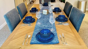 A dining room with a wooden table set for six, blue tableware, and a chandelier. - Spacious Yosemite Lodge –Arcades + EV Charger + 3B2B + Private 1 Acre +Game Room (Oakhurst)