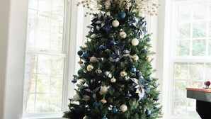 A Christmas tree decorated with blue and gold ornaments in a room with large windows. - Spacious Yosemite Lodge –Arcades + EV Charger + 3B2B + Private 1 Acre +Game Room (Oakhurst)