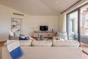 Relax in your spacious living room with plush seating, modern amenities, and glass doors opening to your private outdoor space.