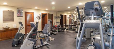 Un gimnasio con equipo de ejercicio diverso, incluyendo cintas de correr y máquinas de pesas.