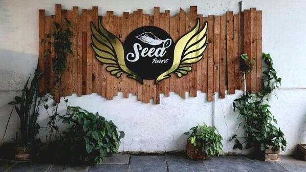 A wooden wall with a logo for 'Seed Resort' featuring wings. - Seed Resort (Shrirangapattana)