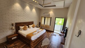 A hotel room with a brick wall, a wooden bed, a ceiling fan, and a sliding glass door to the outside. - Seed Resort (Shrirangapattana)