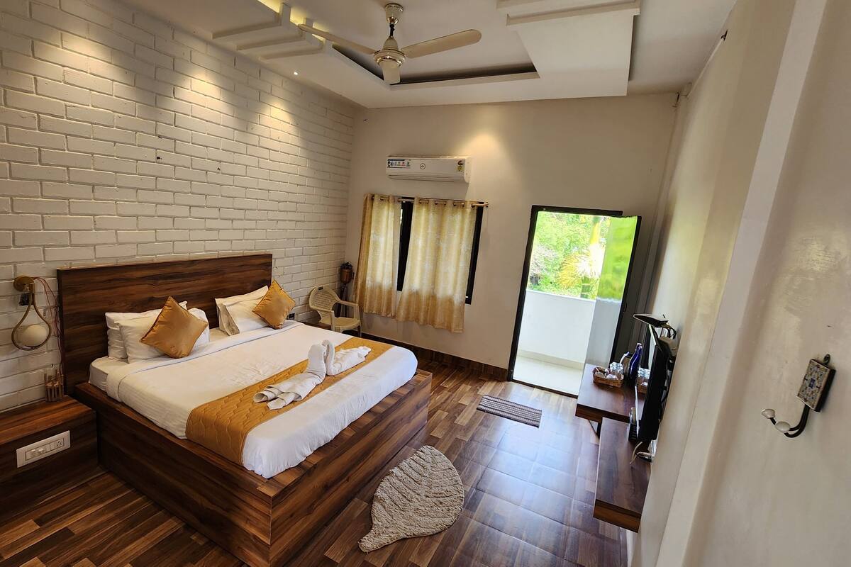 A hotel room with a brick wall, a wooden bed, a ceiling fan, and a sliding glass door to the outside.