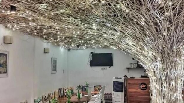 A conference room with long tables and chairs, a projector screen, and a decorative tree-like structure with lights. - Seed Resort (Shrirangapattana)