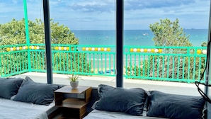 Un balcon avec deux lits, une petite table et une vue sur la mer.