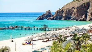 Une plage avec une jetée, des parasols et un poste de surveillance pour les sauveteurs.