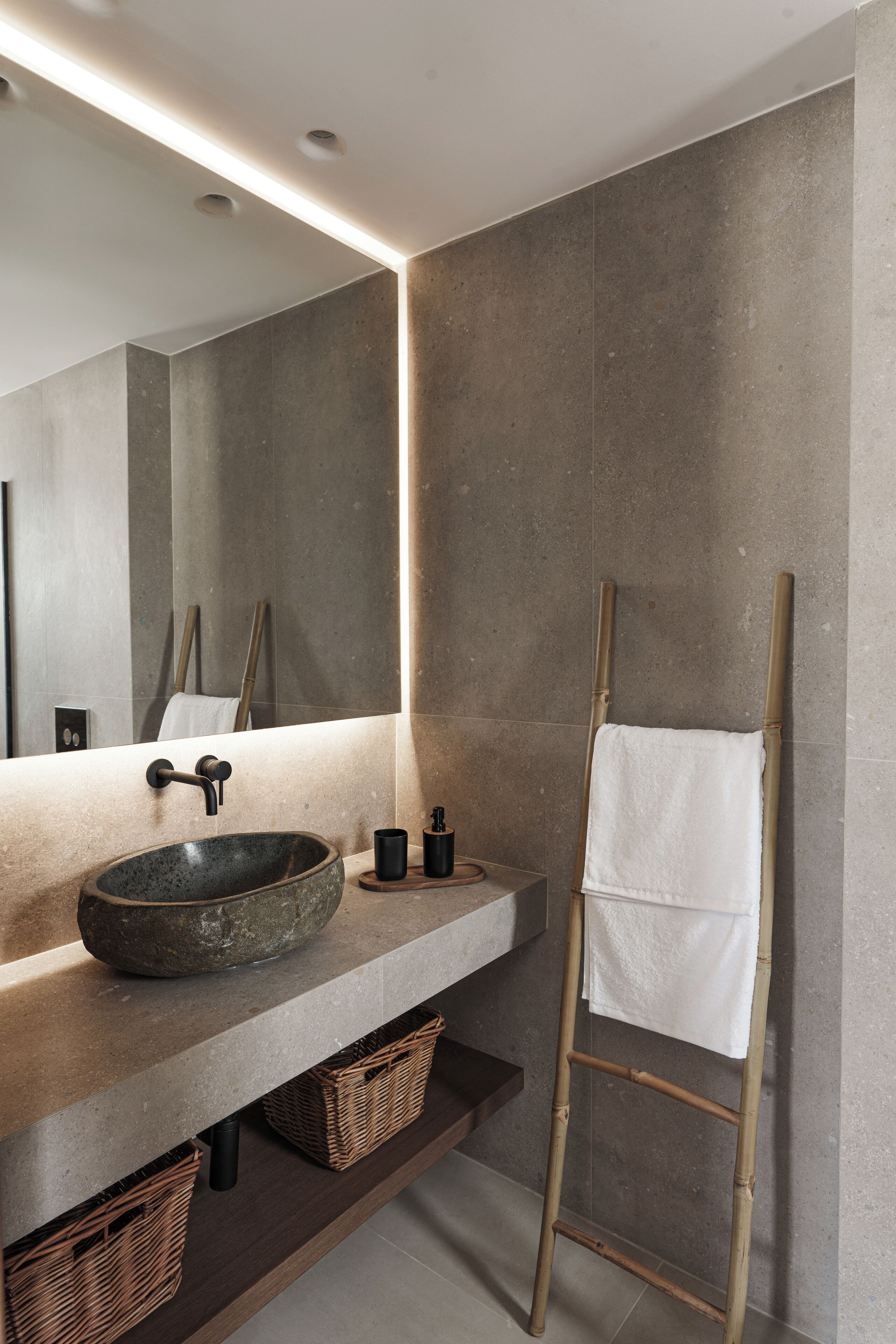 Une salle de bain moderne avec un lavabo en pierre, une échelle en bois et un grand miroir.