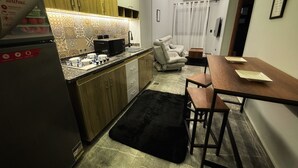 A compact kitchen with a refrigerator, microwave, and sink. There is a dining area with a table and chairs. - Private Jacuzzi 1BDR suite with garden at New Cairo (New Cairo City)
