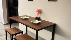 A modern dining area with a wooden table and two matching chairs, a small potted plant, and two framed pictures on the wall. - Private Jacuzzi 1BDR suite with garden at New Cairo (New Cairo City)