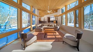 A spacious living area with a large sectional sofa, a coffee table, and a fireplace. - Villa Lily (Hakuba)