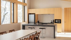 A modern kitchen with a central island, wooden cabinets, and a dining area with chairs. - Villa Lily (Hakuba)