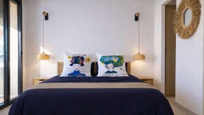Ein Bett mit zwei Kissen, einem runden Spiegel und zwei Wandleuchten.