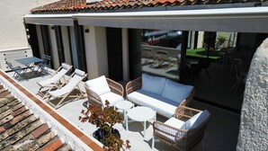 Ein überdachter Außenbereich mit Lounge-Stühlen, einer Couch und einem kleinen Tisch.