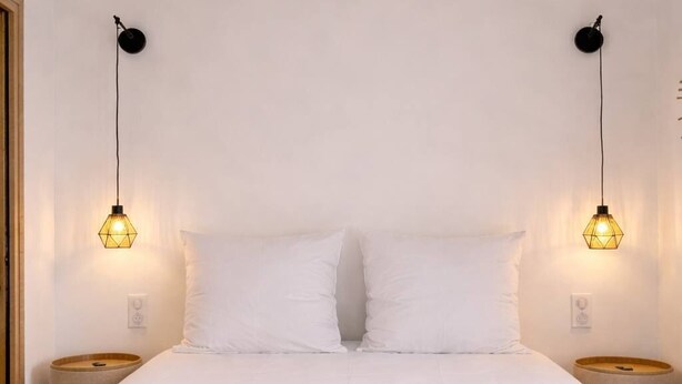 Ein Schlafzimmer mit einem Bett, zwei Nachttischlampen und einem Holzkopfteil.