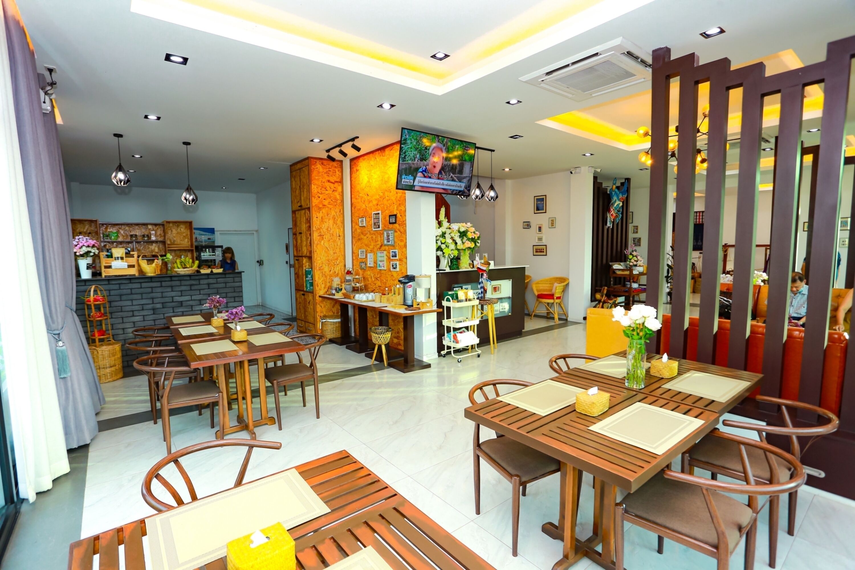 A modern restaurant with wooden furniture, a TV screen, and a variety of decorations.
