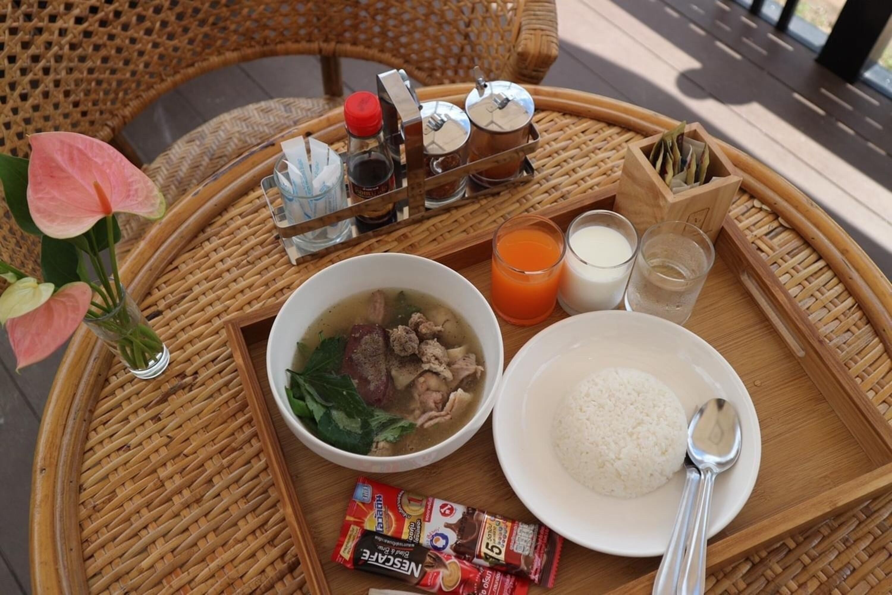 Una bandeja con un bol de sopa, un plato de arroz, un vaso de zumo de naranja y una botella de leche.