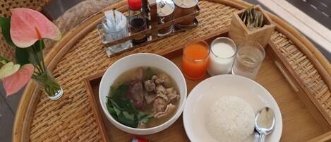 Una bandeja con un bol de sopa, un plato de arroz, un vaso de zumo de naranja y una botella de leche.