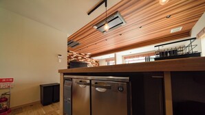 Een keuken met houten plafond, roestvrijstalen apparatuur en een zichtbare brandblusser.