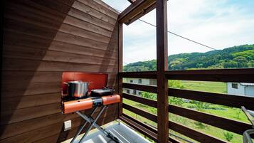 Ein Holzbalkon mit Grill und Kochgeschirr.