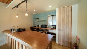 Een moderne keuken met een houten kookeiland, hanglampen, inbouwplanken en een magnetron.