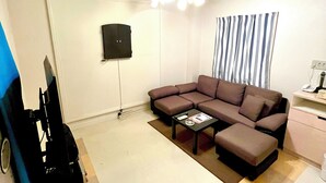 A living room with a sectional sofa, a coffee table, a flat-screen TV, and a ceiling fan. - HOTEL ANNOIE (Yoshioka)