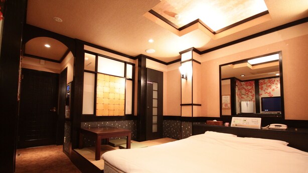 A hotel room with a large bed, a bedside table, a mirror, and a window with a view of the outside. - HOTEL ANNOIE (Yoshioka)