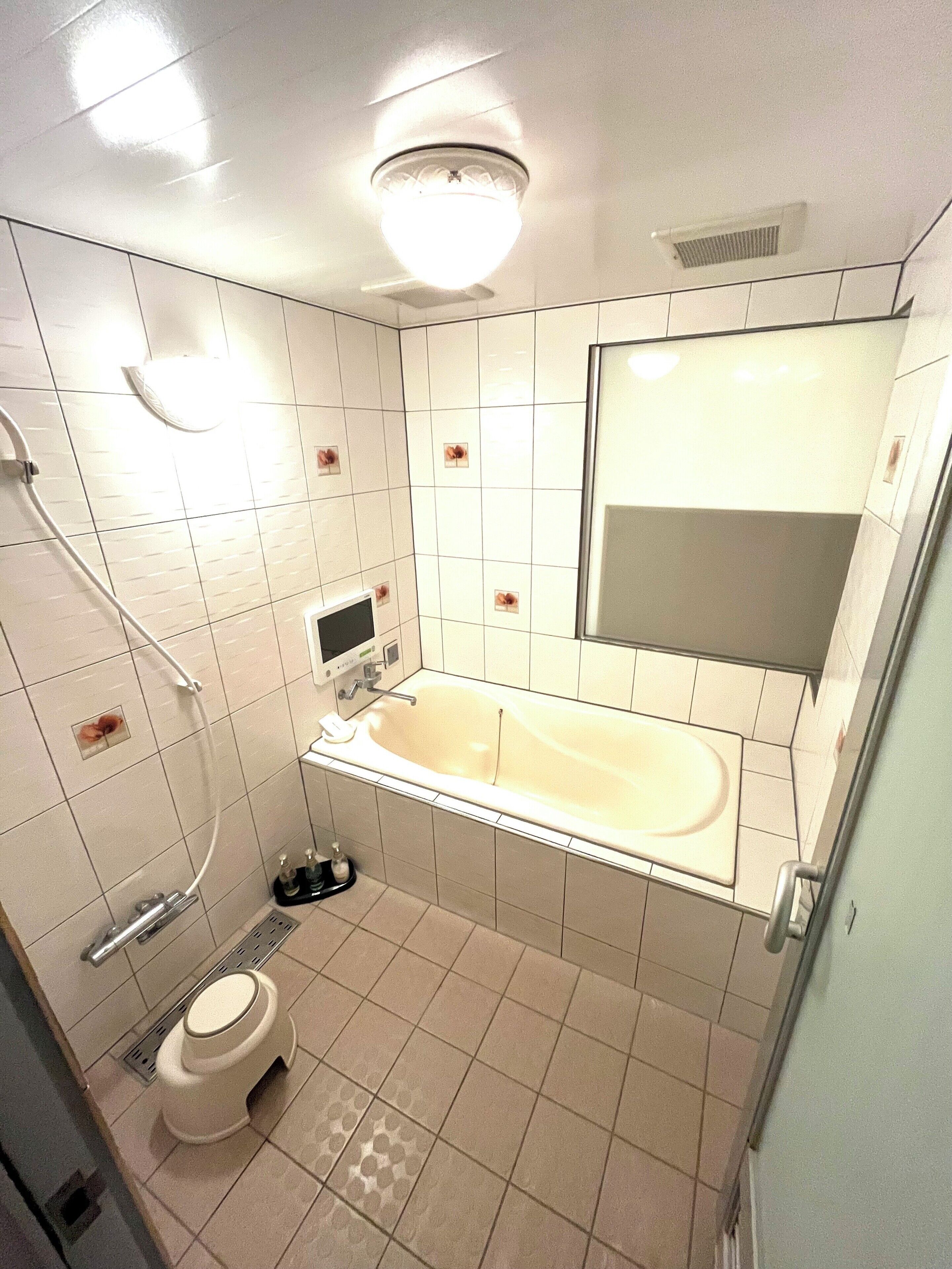 A modern bathroom with a bathtub, toilet, and shower.