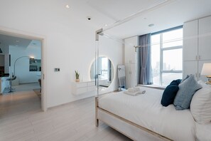 Ein modernes Schlafzimmer mit einem großen Bett, einem begehbaren Kleiderschrank, einem Badezimmer und Blick auf die Stadt.