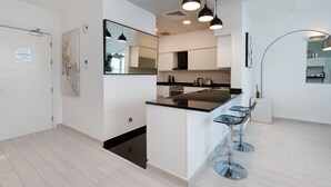 Une cuisine moderne dotée d’un îlot central, de tabourets de bar, de luminaires suspendus et d’un grand miroir.