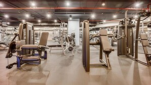 Une salle de sport équipée de divers appareils d’exercice, notamment des bancs de musculation et des poids libres.