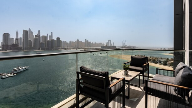 A balcony with a city skyline view, a pool, and a yacht.
