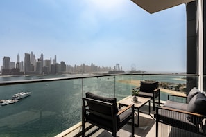 A balcony with a city skyline view, a pool, and a yacht.
