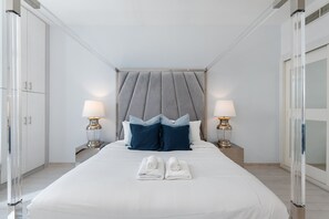 Quarto de hotel com uma cama grande, duas luminárias de cabeceira, uma cabeceira e um par de toalhas sobre a cama.