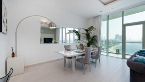 A modern living room with a dining area, large windows, and a view of the city.