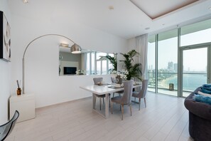 A modern living room with a dining area, large windows, and a view of the city.
