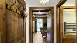 Un pasillo con puertas de madera, un perchero e iluminación decorativa.