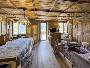 A rustic wooden interior with a dining table, chairs, a sofa, and a television. - Swiss Alpine Retreat & View near Martigny (Salvan)