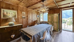 Una habitación de madera con una mesa de comedor, sillas, una araña y vistas a través de una ventana.