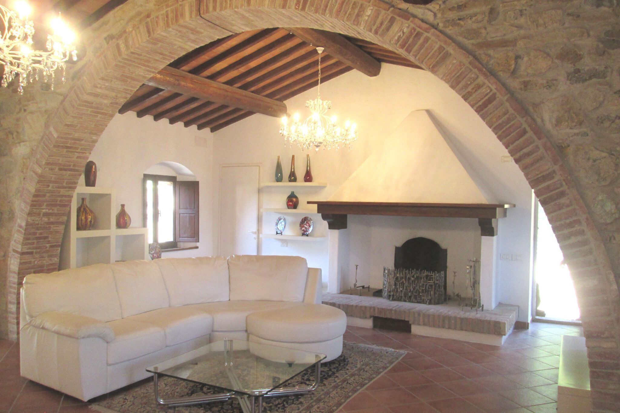 Una sala de estar con un sofá blanco, una mesa de centro de vidrio y una chimenea.
