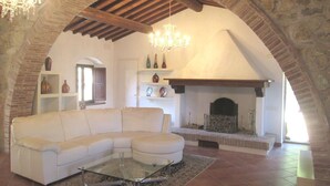 A living room with a white sofa, a glass coffee table, and a fireplace. - Villa in Tuscany with Pool & Olive Groves (Castelnuovo di Val di Cecina (PI))