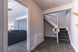 A staircase with a white railing, a welcome mat, and a grey sofa in the background.
