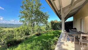 A covered outdoor area with a view of a tree and landscape.