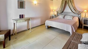 A bedroom with a bed, bedside tables, a small table, and a chair.